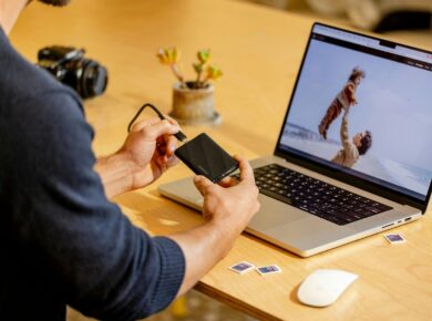 A man sitting at a table with a laptop and cell phone