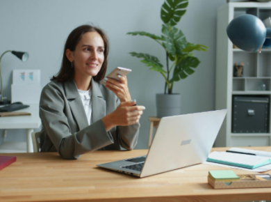 lady holding phone while working on a laptop